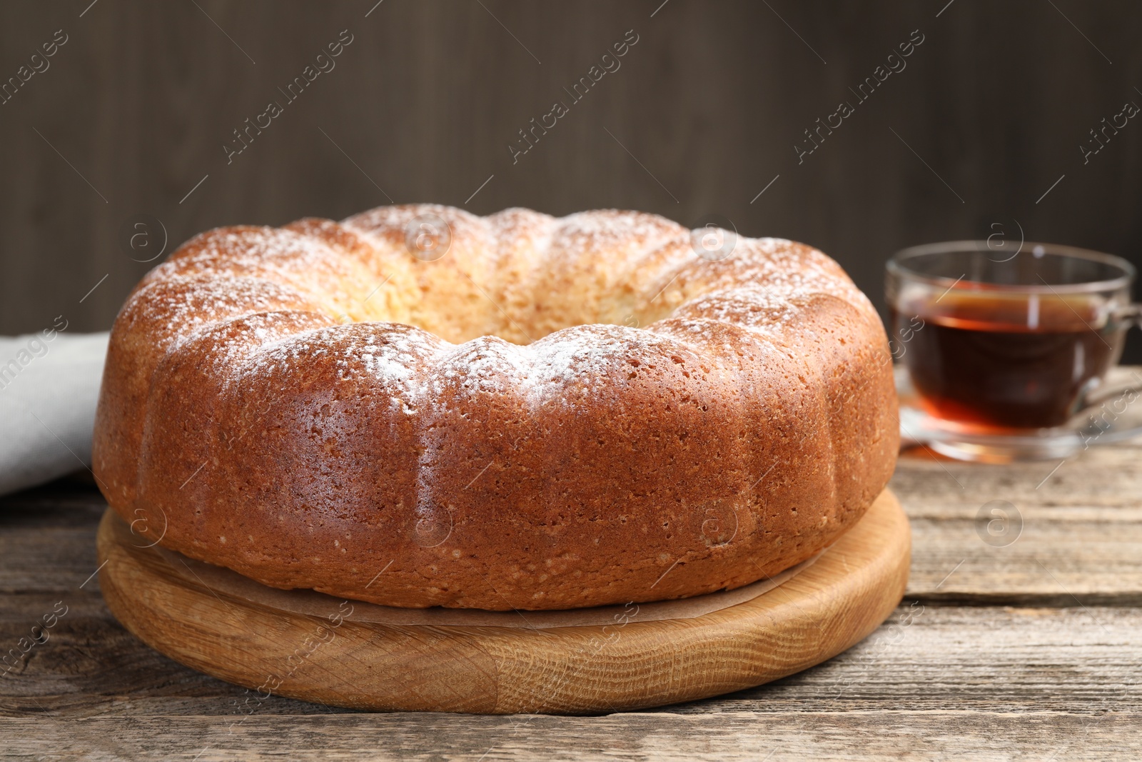 Photo of Freshly baked sponge cake and tea on wooden table, closeup