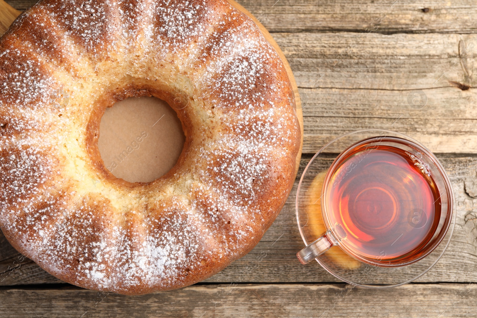 Photo of Freshly baked sponge cake and tea on wooden table, top view