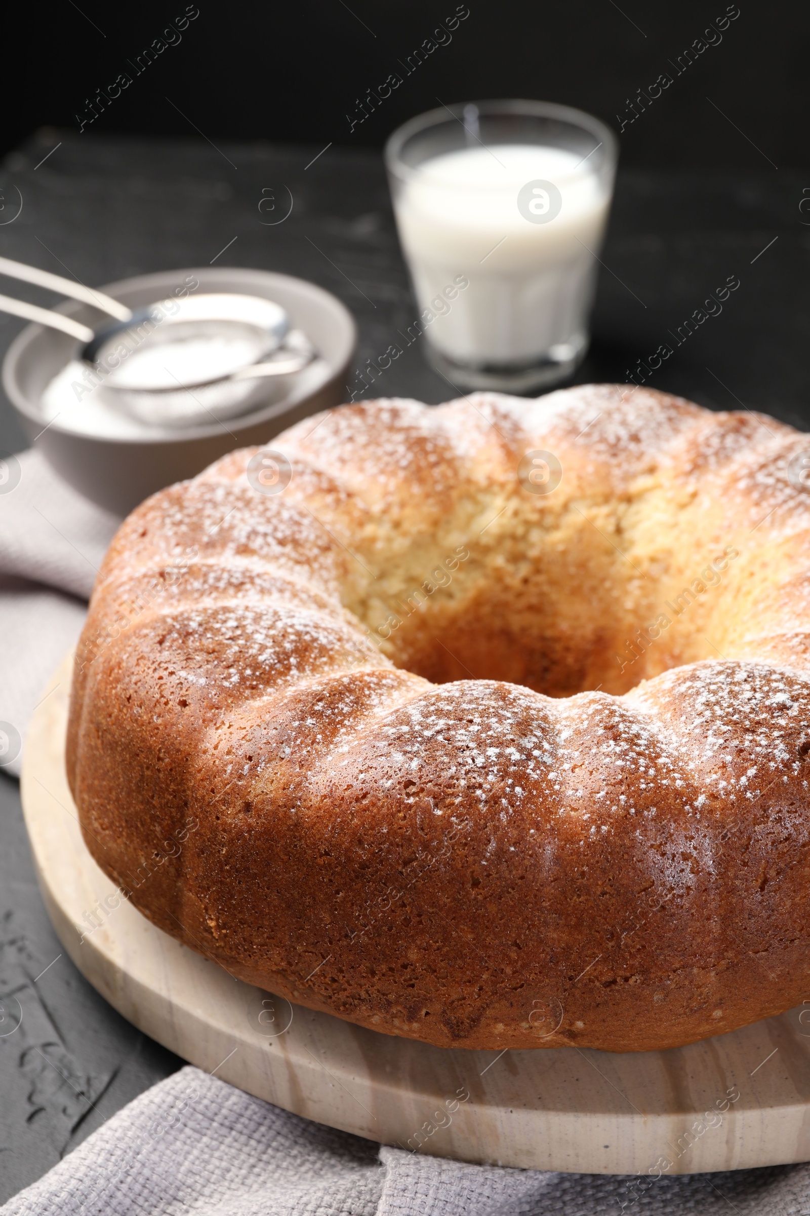 Photo of Freshly baked sponge cake with powdered sugar and milk on table, closeup