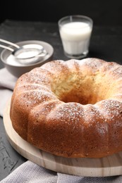 Photo of Freshly baked sponge cake with powdered sugar and milk on table, closeup