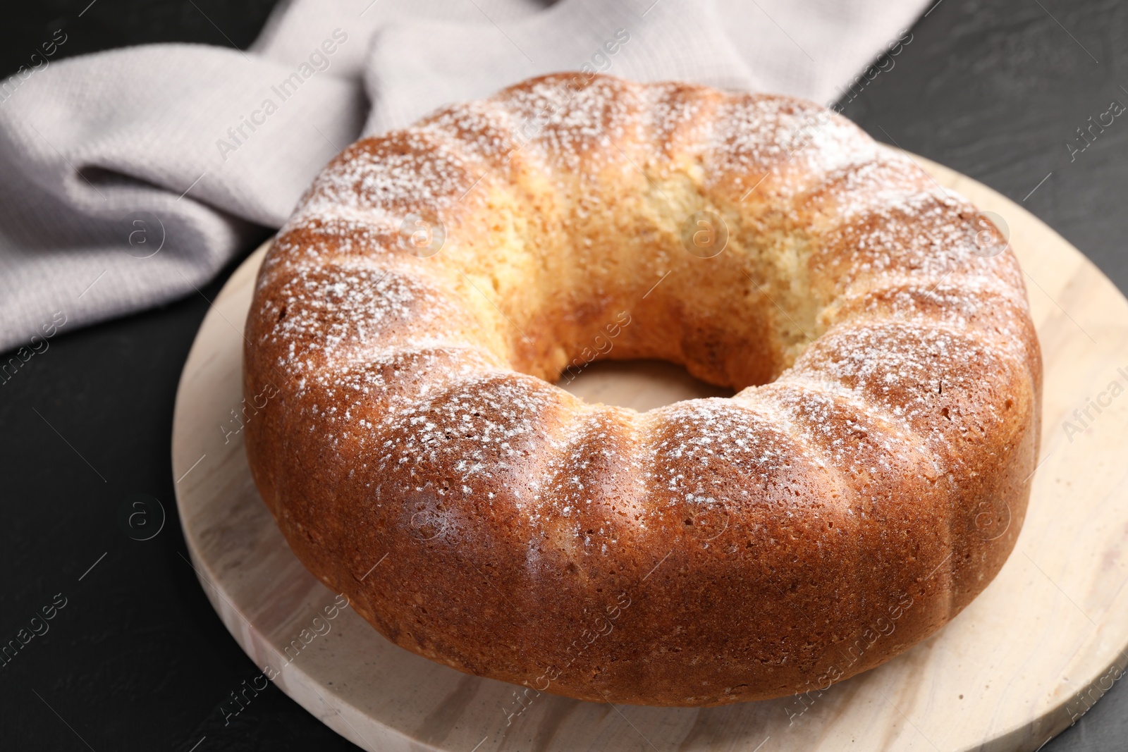 Photo of Freshly baked sponge cake on black table, closeup