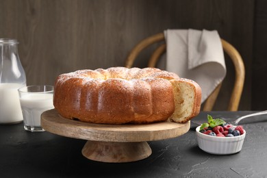 Freshly baked sponge cake, berries, milk and server on black table