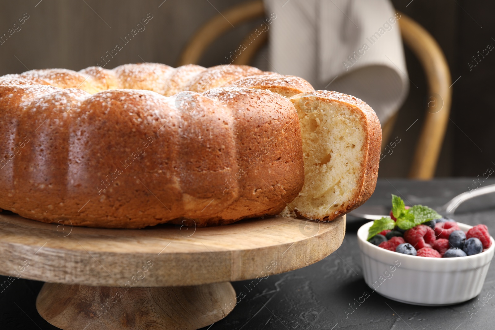 Photo of Freshly baked sponge cake and berries on black table, closeup