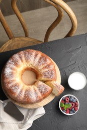 Freshly baked sponge cake, berries, milk and server on black table, top view