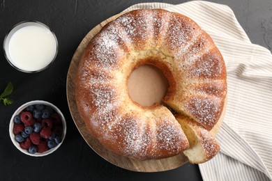 Freshly baked sponge cake, berries and milk on black table, top view