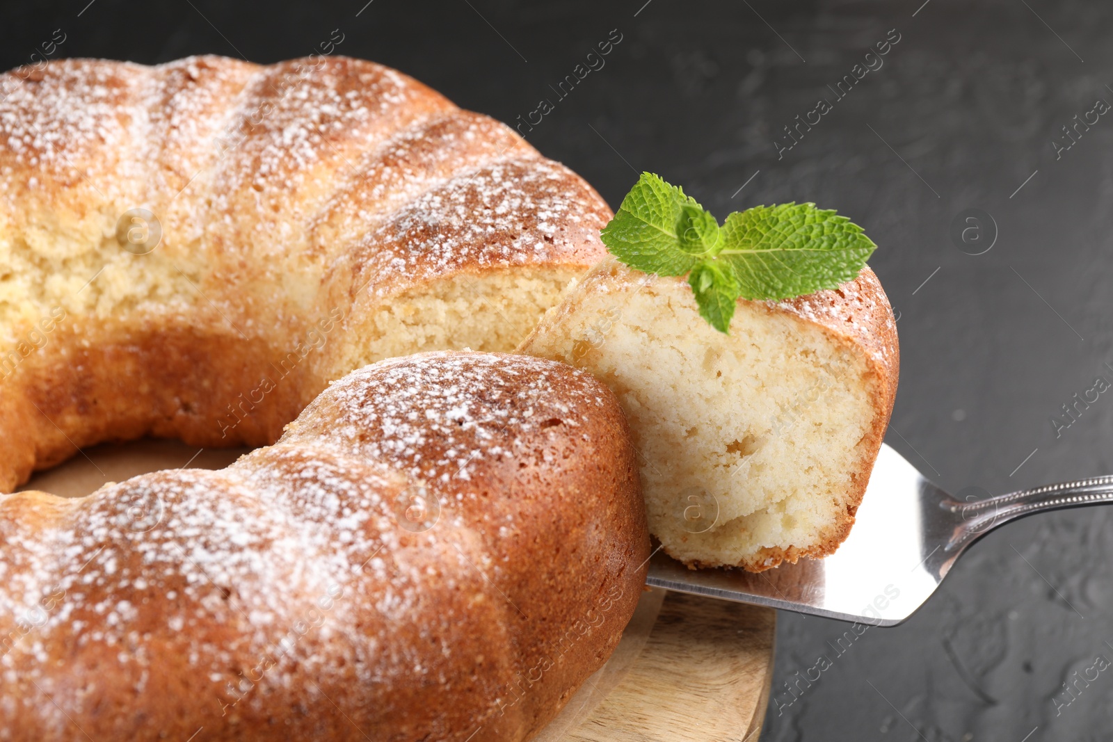 Photo of Taking piece of freshly baked sponge cake at black table, closeup