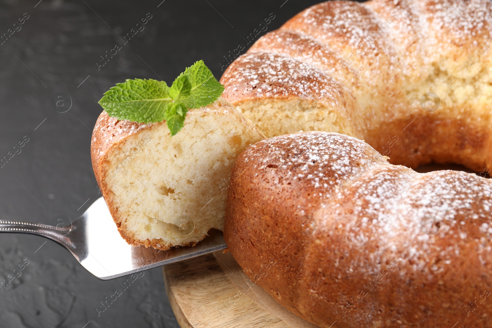 Photo of Taking piece of freshly baked sponge cake at black table, closeup