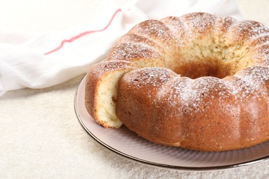 Freshly baked sponge cake on white textured table, closeup