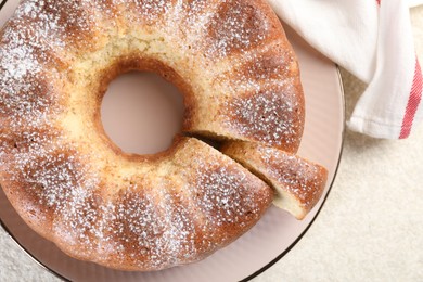 Freshly baked sponge cake on white textured table, top view