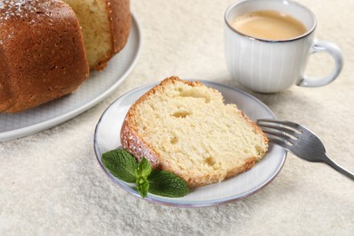 Piece of freshly baked sponge cake, mint and coffee on white textured table, closeup