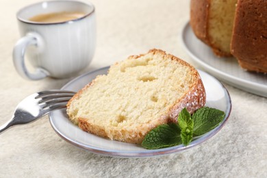 Piece of freshly baked sponge cake, mint and coffee on white textured table, closeup