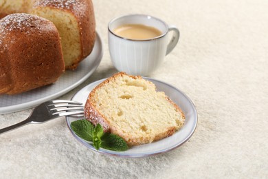 Piece of freshly baked sponge cake, mint and coffee on white textured table, closeup