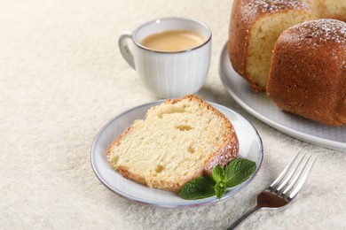 Piece of freshly baked sponge cake, mint and coffee on white textured table, closeup