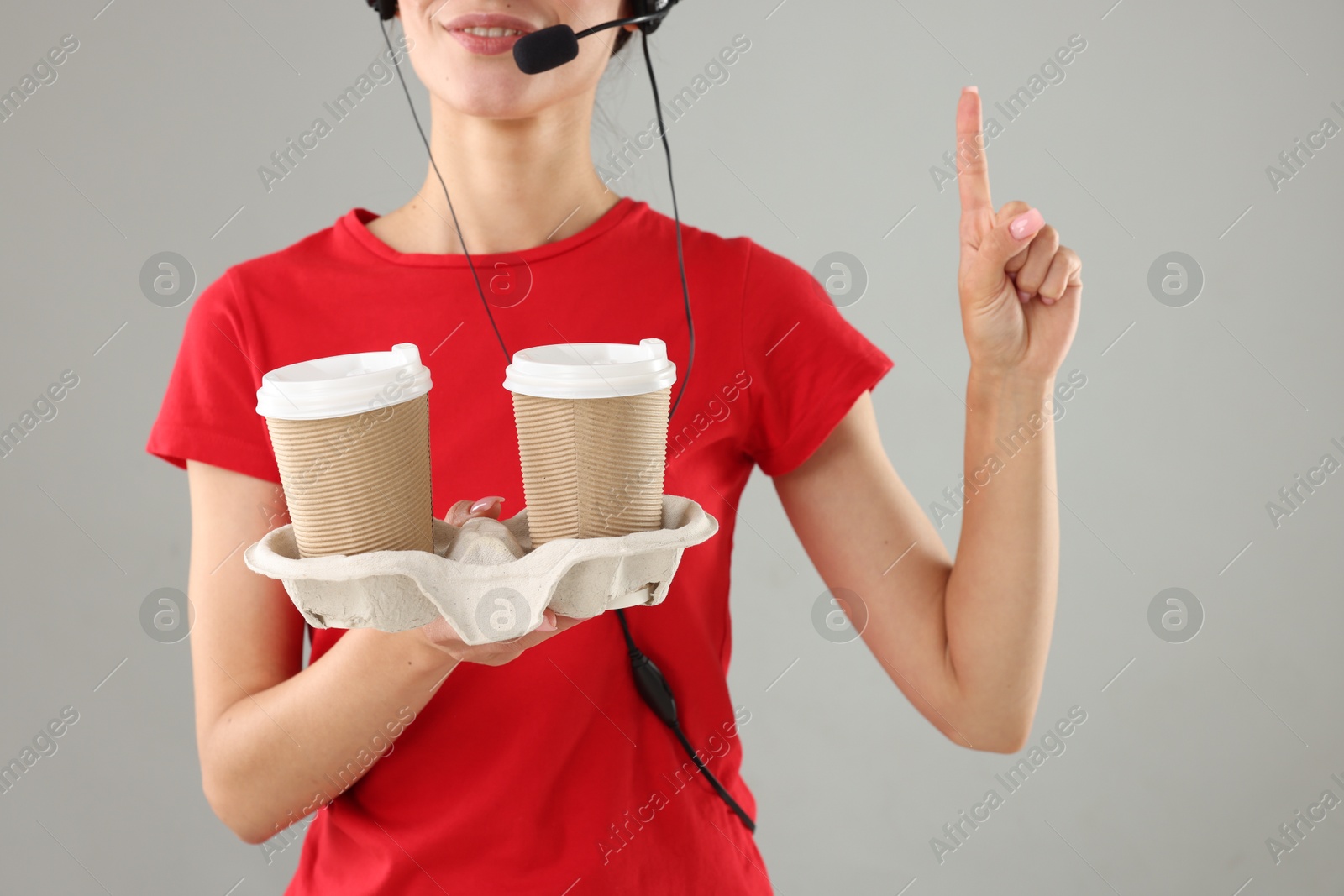 Photo of Fast-food worker with paper cups on gray background, closeup