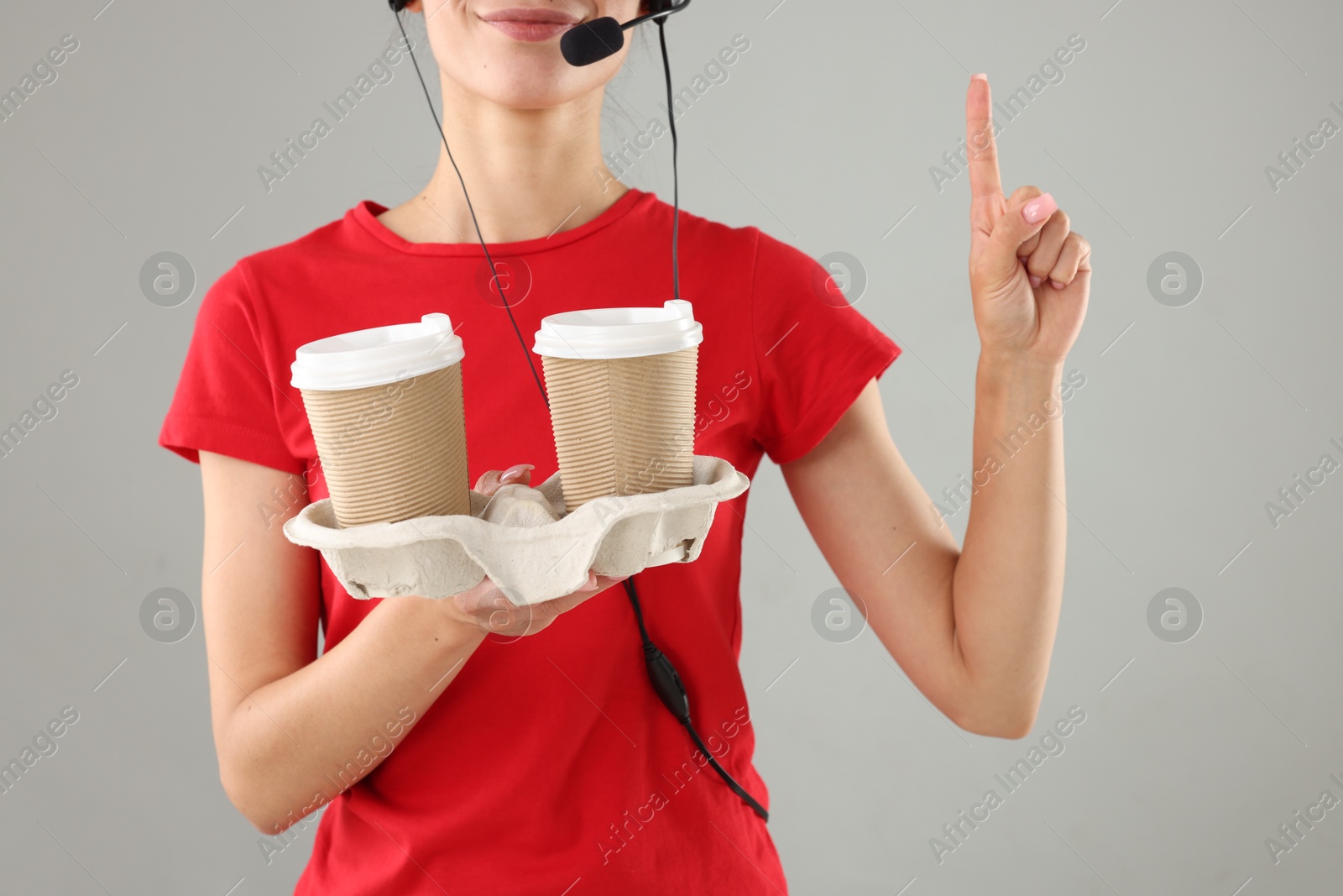 Photo of Fast-food worker with paper cups on gray background, closeup