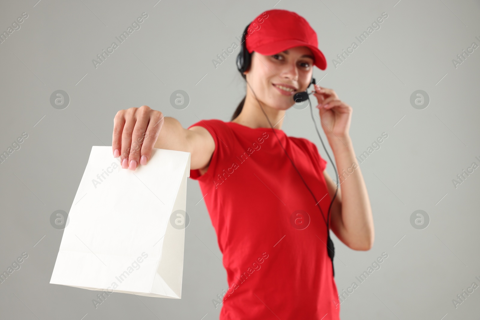 Photo of Fast-food worker with paper bag on gray background, selective focus