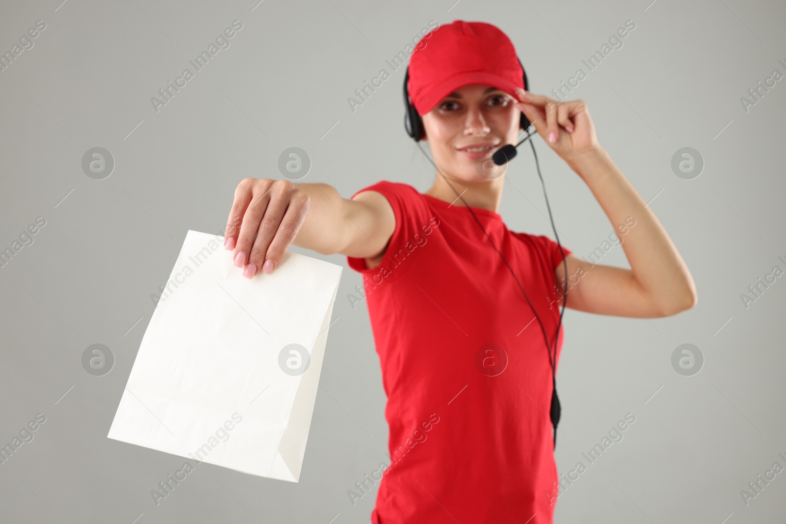 Photo of Fast-food worker with paper bag on gray background, selective focus