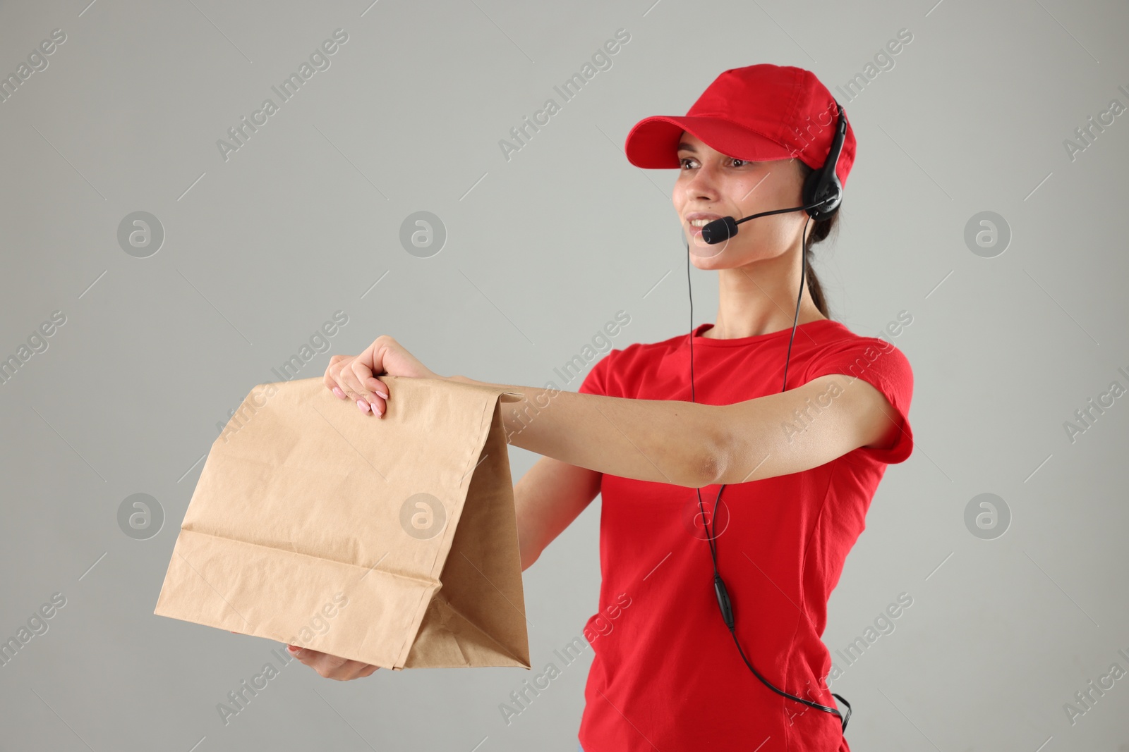 Photo of Fast-food worker with paper bag on gray background