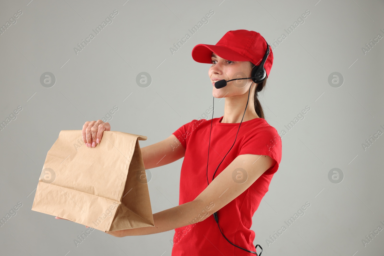 Photo of Fast-food worker with paper bag on gray background