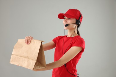 Fast-food worker with paper bag on gray background