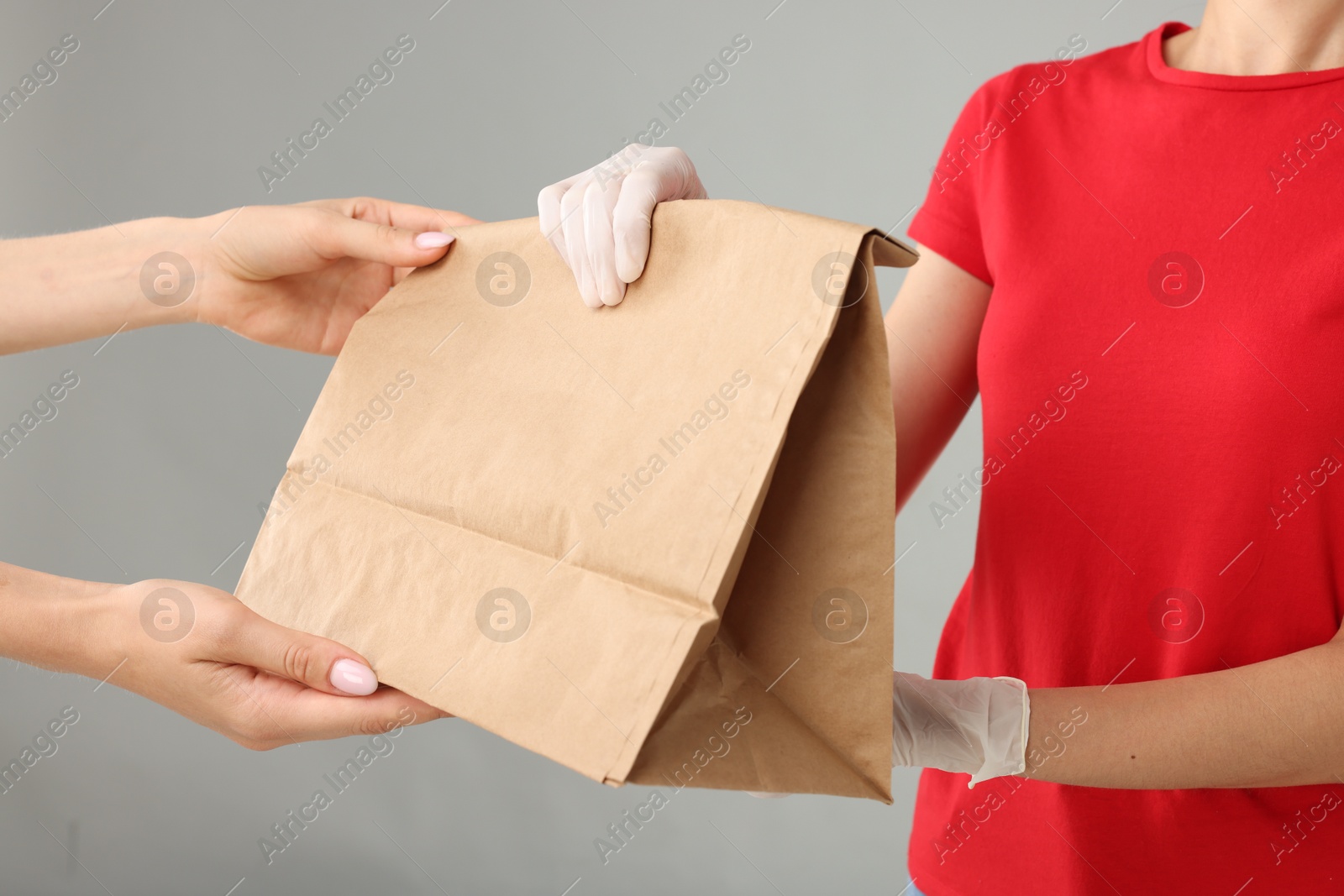 Photo of Fast-food worker giving customer's order on gray background, closeup