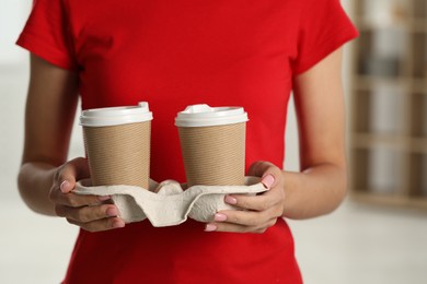 Photo of Fast-food worker with paper cups indoors, closeup