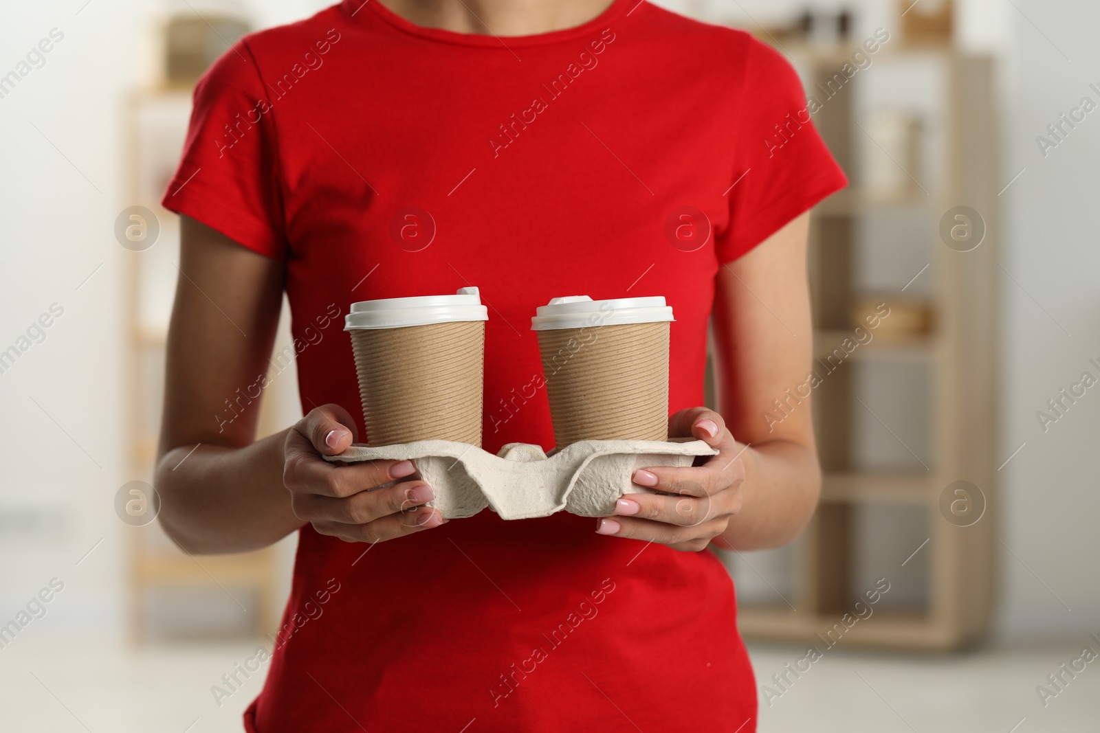 Photo of Fast-food worker with paper cups indoors, closeup