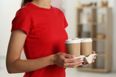 Fast-food worker with paper cups indoors, closeup