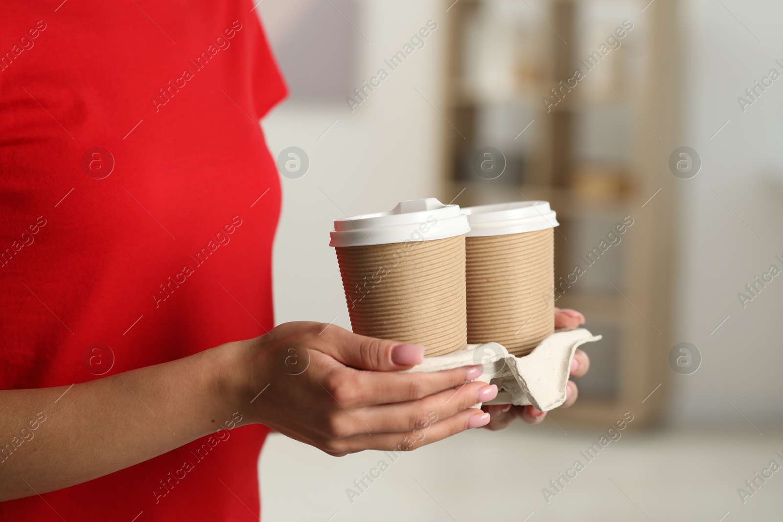 Photo of Fast-food worker with paper cups indoors, closeup