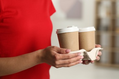 Photo of Fast-food worker with paper cups indoors, closeup