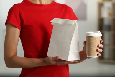 Fast-food worker with paper bag and cup indoors, closeup