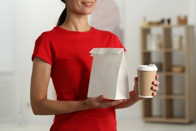 Fast-food worker with paper bag and cup indoors, closeup