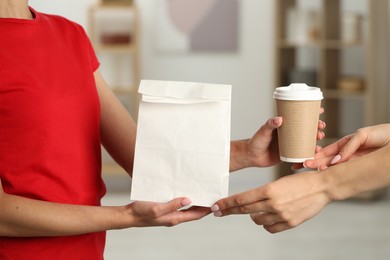 Fast-food worker giving customer's order indoors, closeup