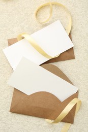 Photo of Blank cards, envelopes and ribbon on beige table, flat lay