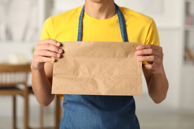 Fast-food worker with paper bag indoors, closeup