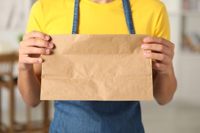 Photo of Fast-food worker with paper bag indoors, closeup