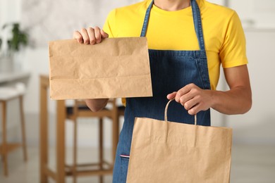 Fast-food worker with paper bags indoors, closeup