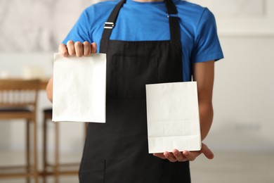 Fast-food worker with paper bags indoors, closeup