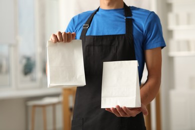 Photo of Fast-food worker with paper bags indoors, closeup