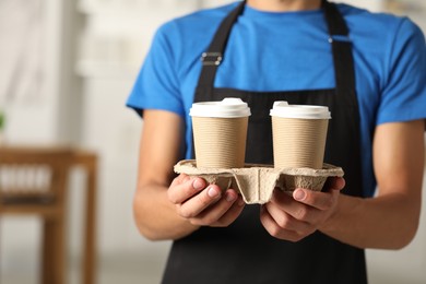 Fast-food worker with paper cups indoors, closeup