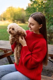 Photo of Smiling woman with cute dog on bench in autumn park