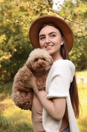 Smiling woman with cute dog in autumn park