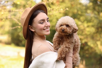 Smiling woman with cute dog in autumn park