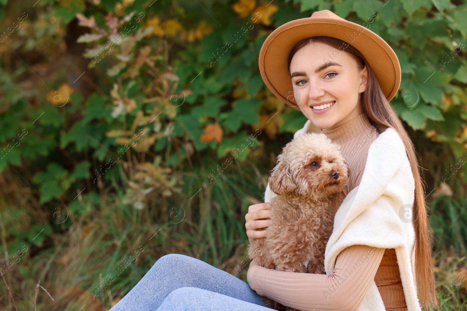 Photo of Smiling woman with cute dog in autumn park. Space for text