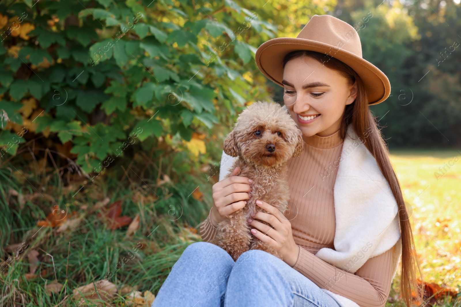 Photo of Smiling woman with cute dog in autumn park. Space for text