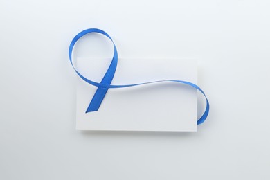 Photo of Blank card and blue ribbon on white background, top view