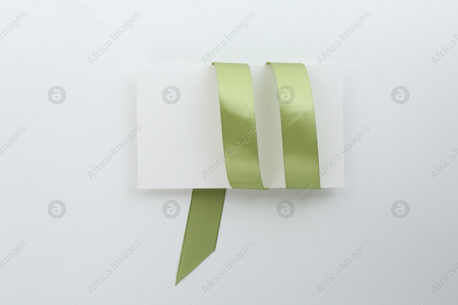 Photo of Blank card and olive ribbon on white background, top view