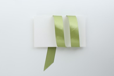 Photo of Blank card and olive ribbon on white background, top view