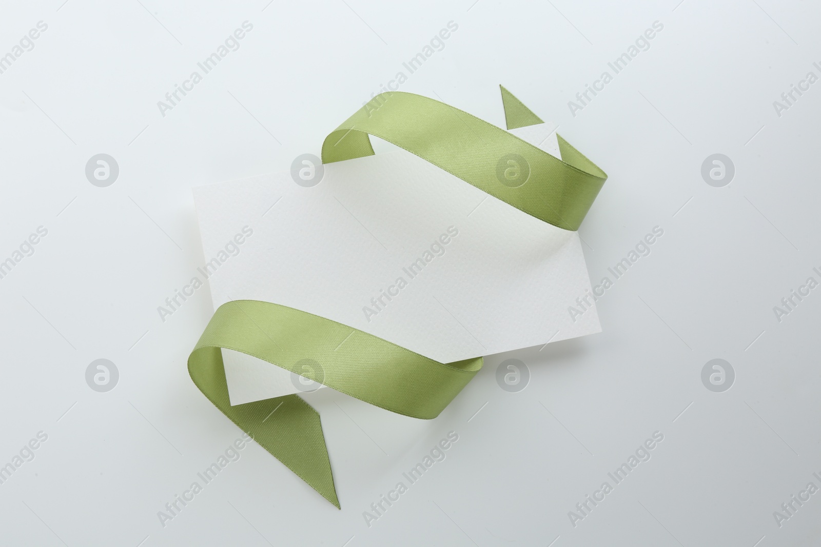 Photo of Blank card and olive ribbon on white background, top view