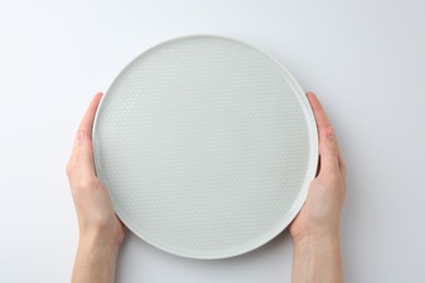 Woman with empty ceramic plate on white background, top view